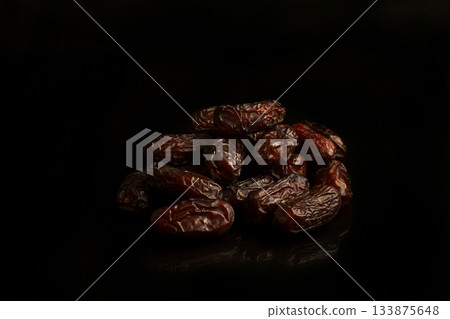 Dates on a black background. Dried fruits. Dried dates lie next to each other 133875648