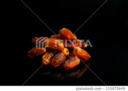 Dates on a black background. Dried fruits. Dried dates lie next to each other Dates on a black background. Dried fruits. Dried dates lie next to each other 133875649