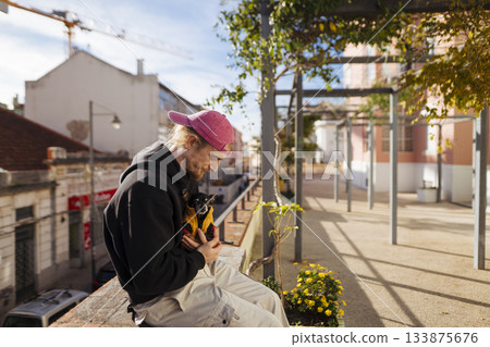 Teenager in pink hat reviews cityscape from balcony edge 133875676
