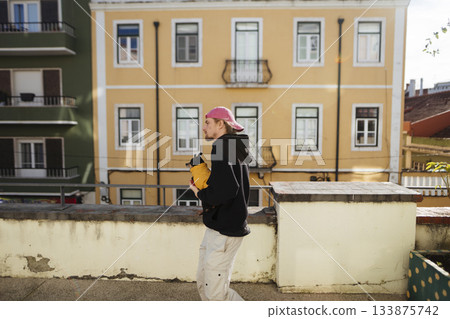 Male pedestrian examines alerts against pastel city setting at sunset Male pedestrian examines alerts against pastel city setting at sunset 133875742