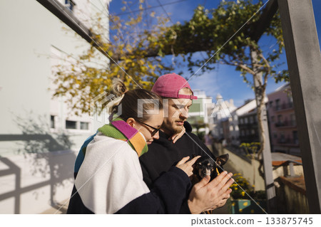 Couple collaborating over phone content amidst sunny outdoor setting 133875745