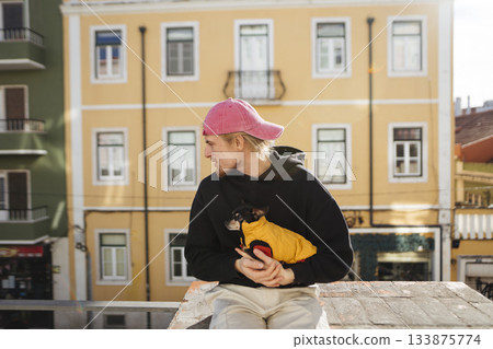 Bright afternoon scene of young man hugging puppy on building rooftop ledge 133875774