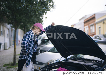 Youthful Caucasian male ensures car safety features are operational Youthful Caucasian male ensures car safety features are operational 133875790