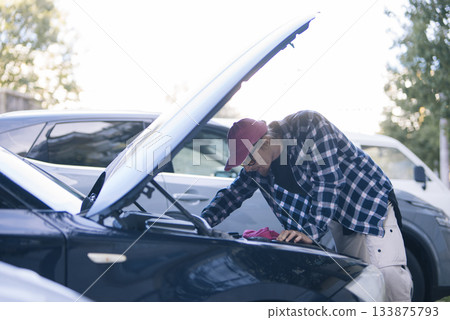 Vehicle technician diagnosing engine issues during tranquil evening hours Vehicle technician diagnosing engine issues during tranquil evening hours 133875793