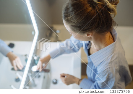 Caucasian female executing skincare steps with concentration and care Caucasian female executing skincare steps with concentration and care 133875796