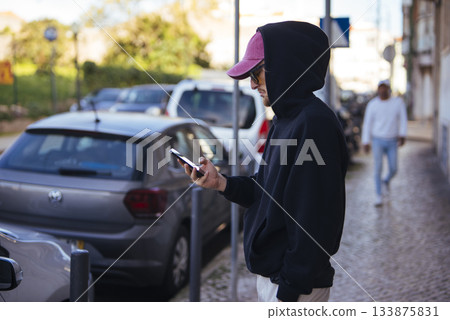 Young adult wearing casual clothing interacting with mobile device outdoors 133875831