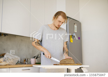 Person with tattoos and casual clothing prepares morning meal at home 133875847
