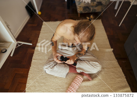 Individual with tattoos organizing filming accessories at home 133875872