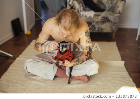 Authentic moment of owner caring for small dog in sunny living space 133875878