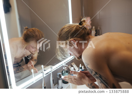 An unclothed individual contemplating in reflective illumination 133875888
