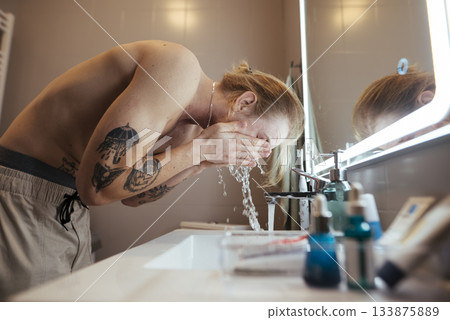 Male grooming oneself at early morning mirror with water droplets 133875889
