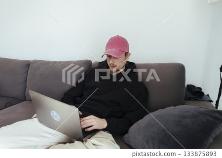 Young man concentrating on laptop in peaceful apartment setting Young man concentrating on laptop in peaceful apartment setting 133875893