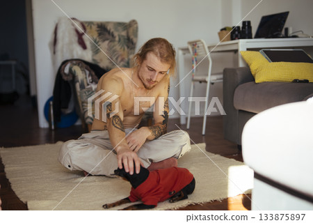 Comfortable home setting featuring man and small playful dog interaction Comfortable home setting featuring man and small playful dog interaction 133875897