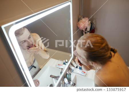 Man maintaining facial hygiene under soothing LED illumination 133875917
