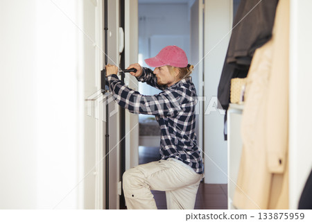 Beginner lock technician engaged in door security training Beginner lock technician engaged in door security training 133875959