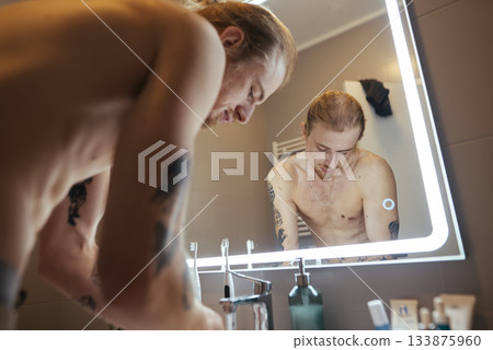 Individual engaged in energetic morning cleansing routine at sink 133875960