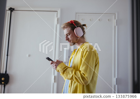 Male individual engaged with smartphone within corridor environment Male individual engaged with smartphone within corridor environment 133875966