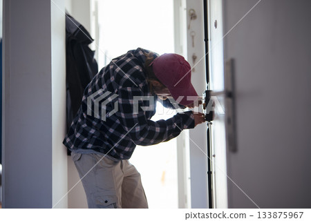 Expert technician repairing interior doorway lock accurately Expert technician repairing interior doorway lock accurately 133875967