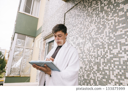 Focused student on balcony surrounded by urban nature environment 133875999