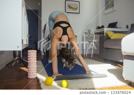 Female practitioner executing deep forward stretch viewed from behind Female practitioner executing deep forward stretch viewed from behind 133876024