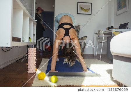 woman transitioning into downward fold showing back and shoulders woman transitioning into downward fold showing back and shoulders 133876069