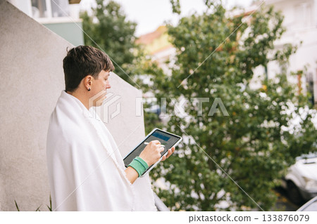 Individual wrapped in cloth views metropolis from high balcony Individual wrapped in cloth views metropolis from high balcony 133876079