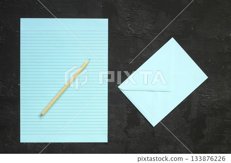 Flat lay, top view, blue sheet and pencil on a gray textured background. Rays of light from the side Flat lay, top view, blue sheet and pencil on a gray textured background. Rays of light from the side 133876226