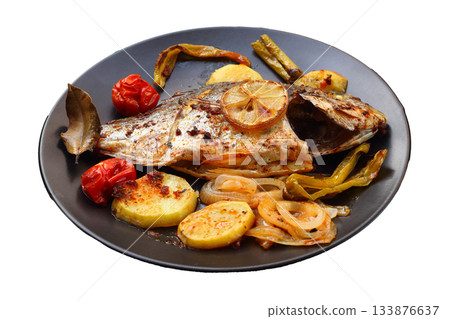 Delicious grilled dorado or sea bream fish with salad, spices, grilled dorada on a black plate. Delicious grilled dorado or sea bream fish with salad, spices, grilled dorada on a black plate. 133876637