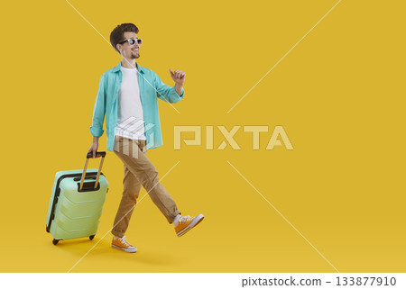 Full length portrait of walking funny man in sunglasses with suitcase on yellow background. Full length portrait of walking funny man in sunglasses with suitcase on yellow background. 133877910