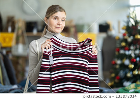 Adult woman chooses sweater in clothing store 133878034