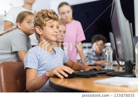 Boy student learning to work on computer in classroom Boy student learning to work on computer in classroom 133878035