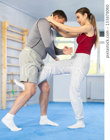 Young girl practicing feet kick method of self-defense in pair with middle-aged man 133878060