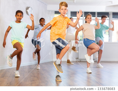 Cheerful tween boy dancing with group of children in choreography class 133878083