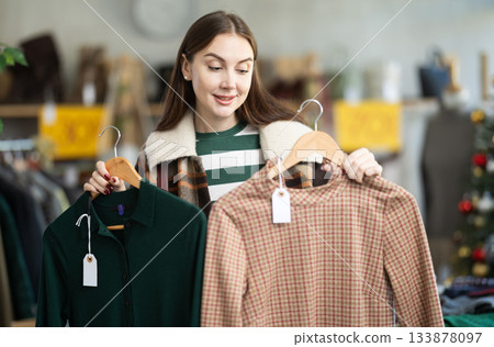 Young woman chooses warm dress in clothing store 133878097