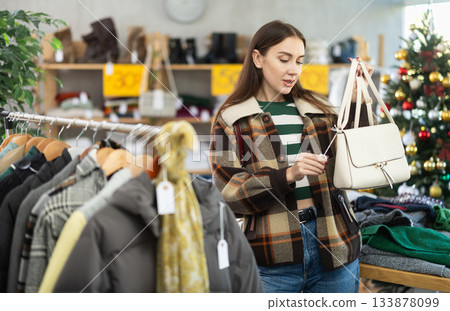 adult woman chooses fashionable handbags in a store against the background of a Christmas tree 133878099