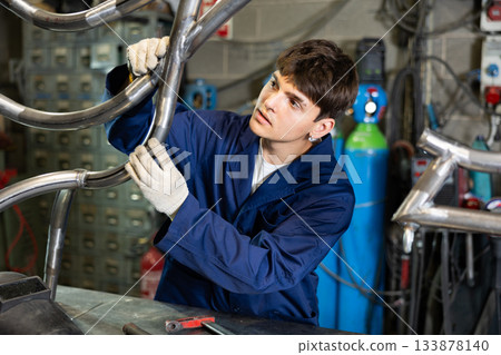 Young guy worker checks welded pipe 133878140