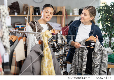 Two women friends browsing goods items and choose elect something autumn outwear Two women friends browsing goods items and choose elect something autumn outwear 133878147