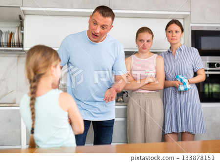 Girl with hair in braids stands in front of parents and listens to instructions about bad behavior Girl with hair in braids stands in front of parents and listens to instructions about bad behavior 133878151