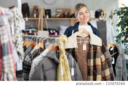 Adult woman chooses plaid jacket in clothing store 133878160