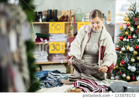 Attentive young woman choosing pantaloons in clothing store Attentive young woman choosing pantaloons in clothing store 133878172