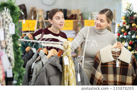 Two women choosing a coat or jacket together in a clothing store for Christmas Two women choosing a coat or jacket together in a clothing store for Christmas 133878203