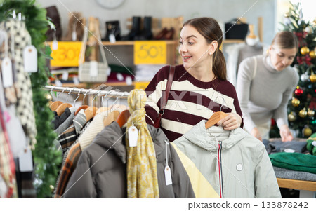 Young woman choosing coat or jacket in clothing store Young woman choosing coat or jacket in clothing store 133878242