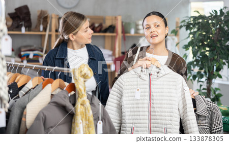 Two adult women choosing outerwear in store 133878305