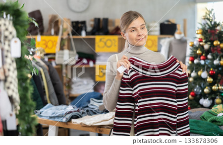 Woman standing in sale area and choosing a sweater 133878306