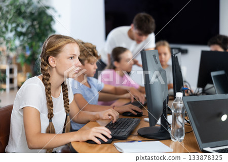 Portrait of teen schoolgirl sitting at table in computer class during lesson, smiling at camera. Concept of teenagers and technologies 133878325