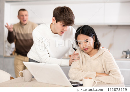 Guy persuades a young girl to stop playing computer games. Upset father in background Guy persuades a young girl to stop playing computer games. Upset father in background 133878359
