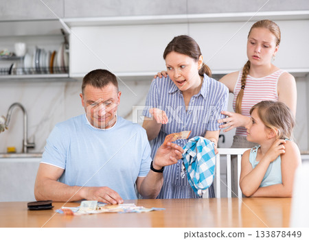 Dissatisfied woman demanding money from perplexed husband at home Dissatisfied woman demanding money from perplexed husband at home 133878449