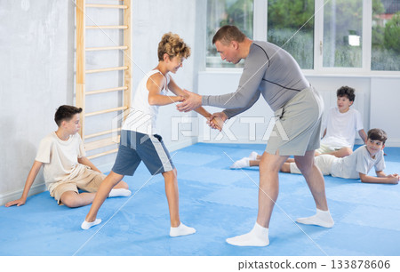 Trainer showing basic techniques to teenagers during simulated self-defense sparring Trainer showing basic techniques to teenagers during simulated self-defense sparring 133878606