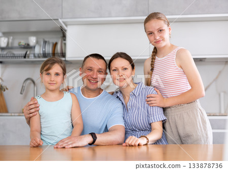 Portrait of happy family - father and mother with two children at table at home Portrait of happy family - father and mother with two children at table at home 133878736