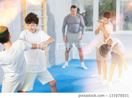 Sporty boys practices self-defence moves in pairs in sporty gym Sporty boys practices self-defence moves in pairs in sporty gym 133878831